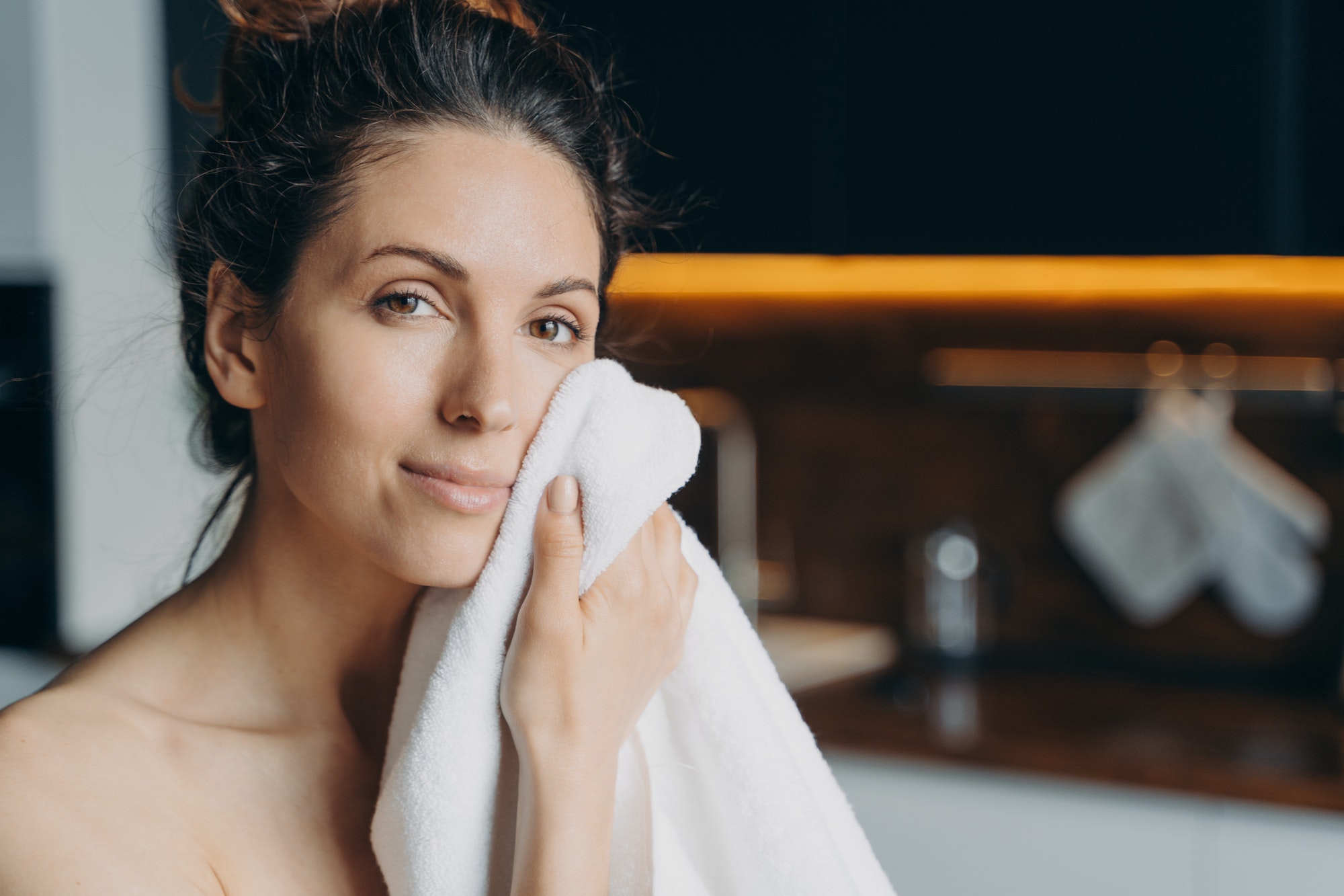 Pretty girl wipe face with towel after shower, enjoy healthy smooth skin at home. Hygiene, skincare